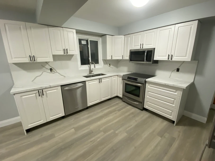 Basic basement kitchen with white cabinets, marble counters, LVP flooring